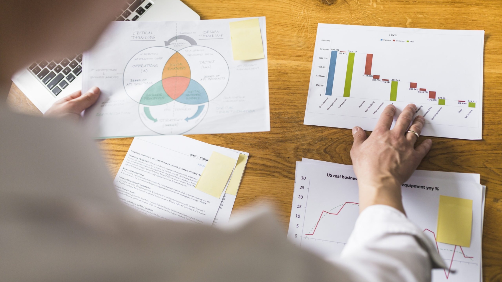 businessperson-s-hand-analyzing-graph-wooden-desk